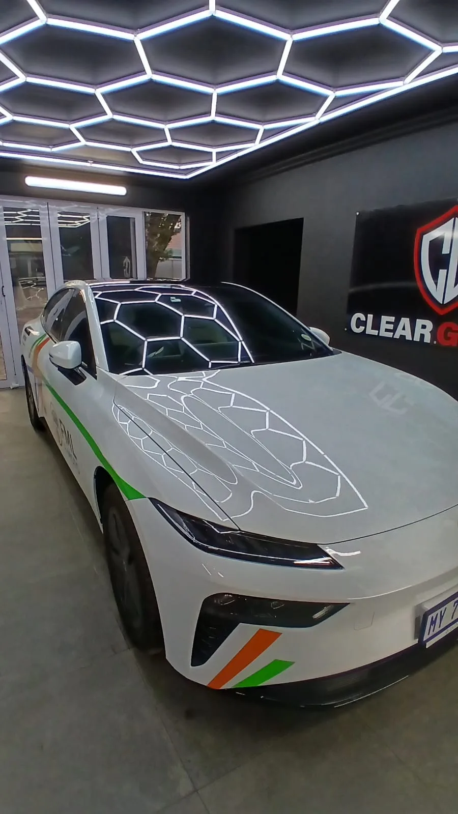 White sports car with green and orange accents in the ClearGuard workshop