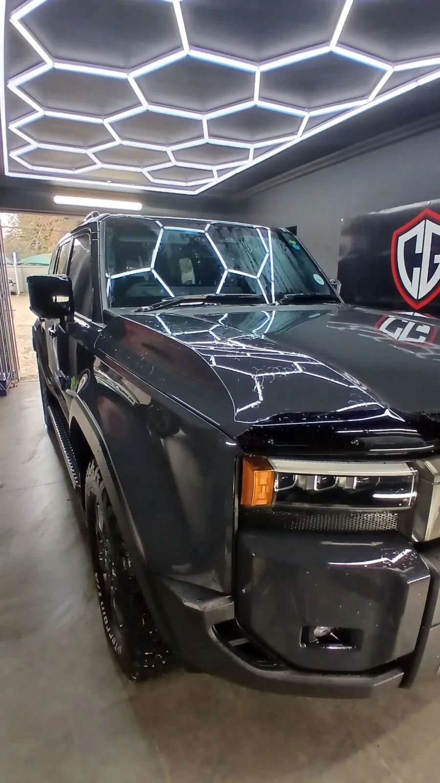 Dark SUV reflecting ceiling lights in the ClearGuard workshop