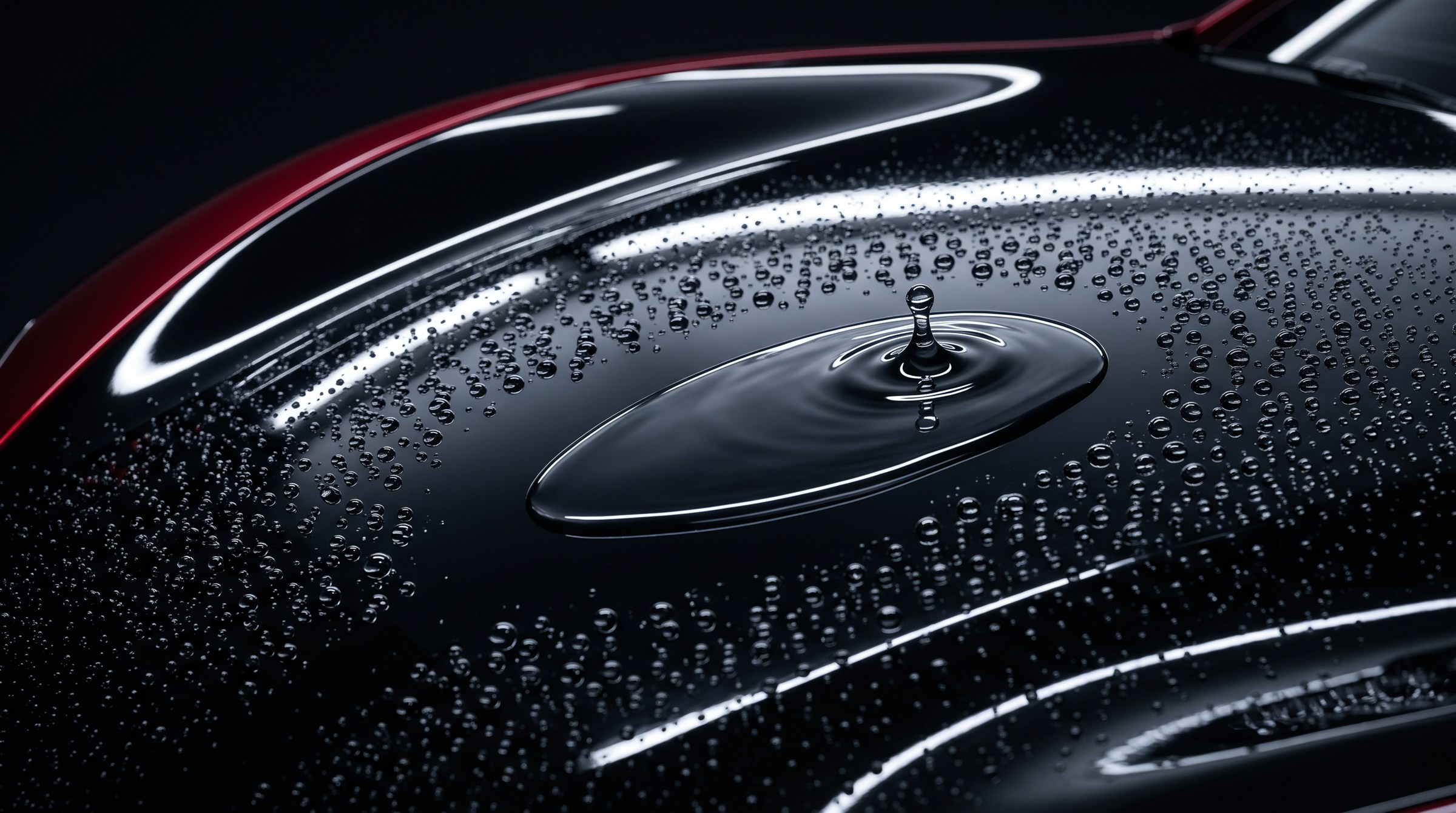 Water droplets and a splash on a glossy black car bonnet