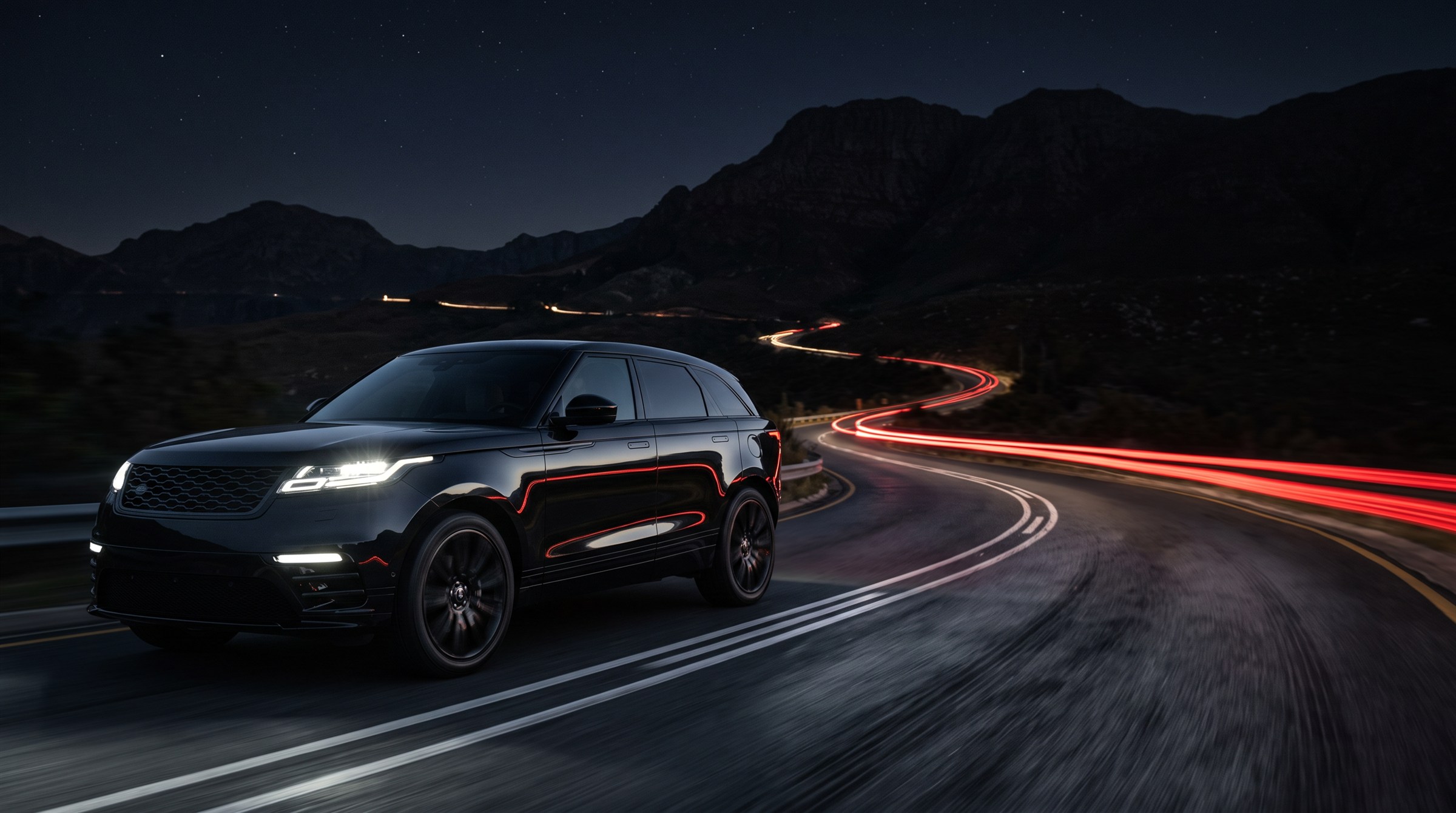 Black SUV on the left of a mountain road at night